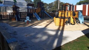 A playground with a climbing structure, slides, and a sandbox area.