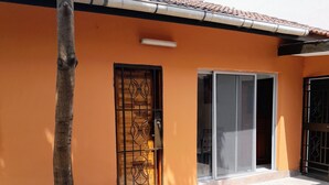 A building with a tiled roof, a metal gate, and a large glass door. - Villa Terracotta - Abidjan - Cocody Riviera (Abidjan)