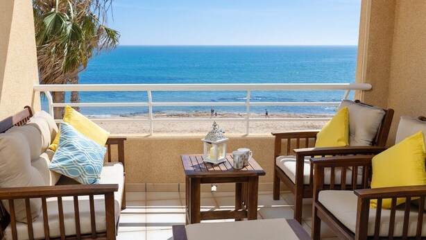 A balcony with a view of the beach, wooden furniture, and a small table with a lantern. - Feel at Home by Fidalsa (La Mata)