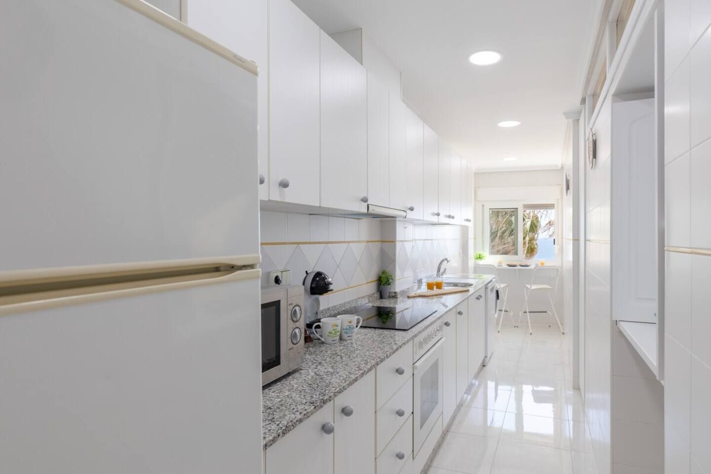 A modern kitchen with white cabinetry, a granite countertop, and a built-in oven.