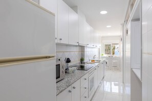 A modern kitchen with white cabinetry, a granite countertop, and a built-in oven. - Feel at Home by Fidalsa (La Mata)