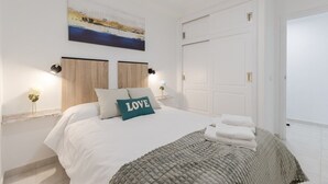 A bedroom with a bed, a painting, two bedside tables, and a white door. - Feel at Home by Fidalsa (La Mata)