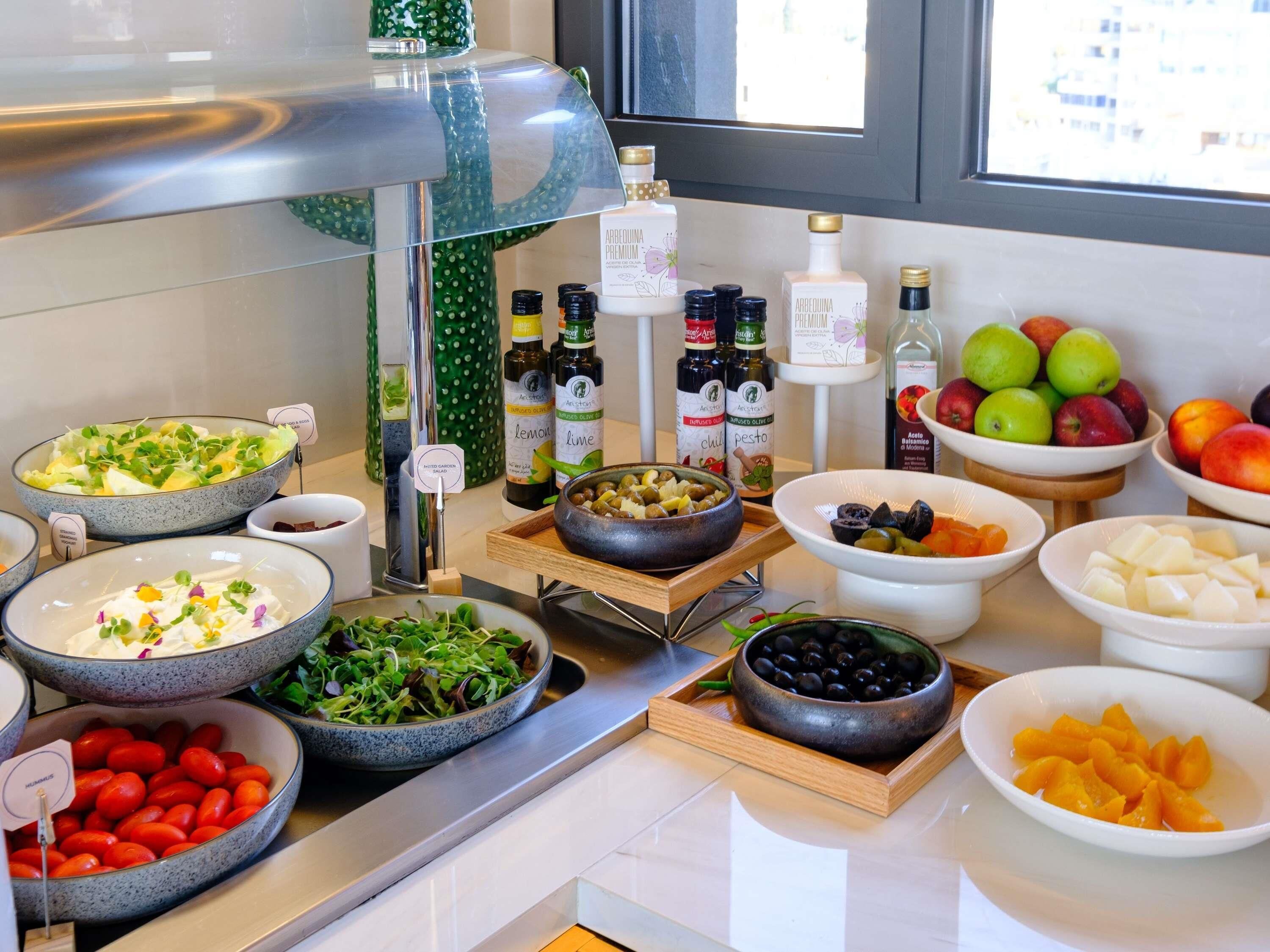 A buffet with various dishes, including salads, fruits, and condiments.