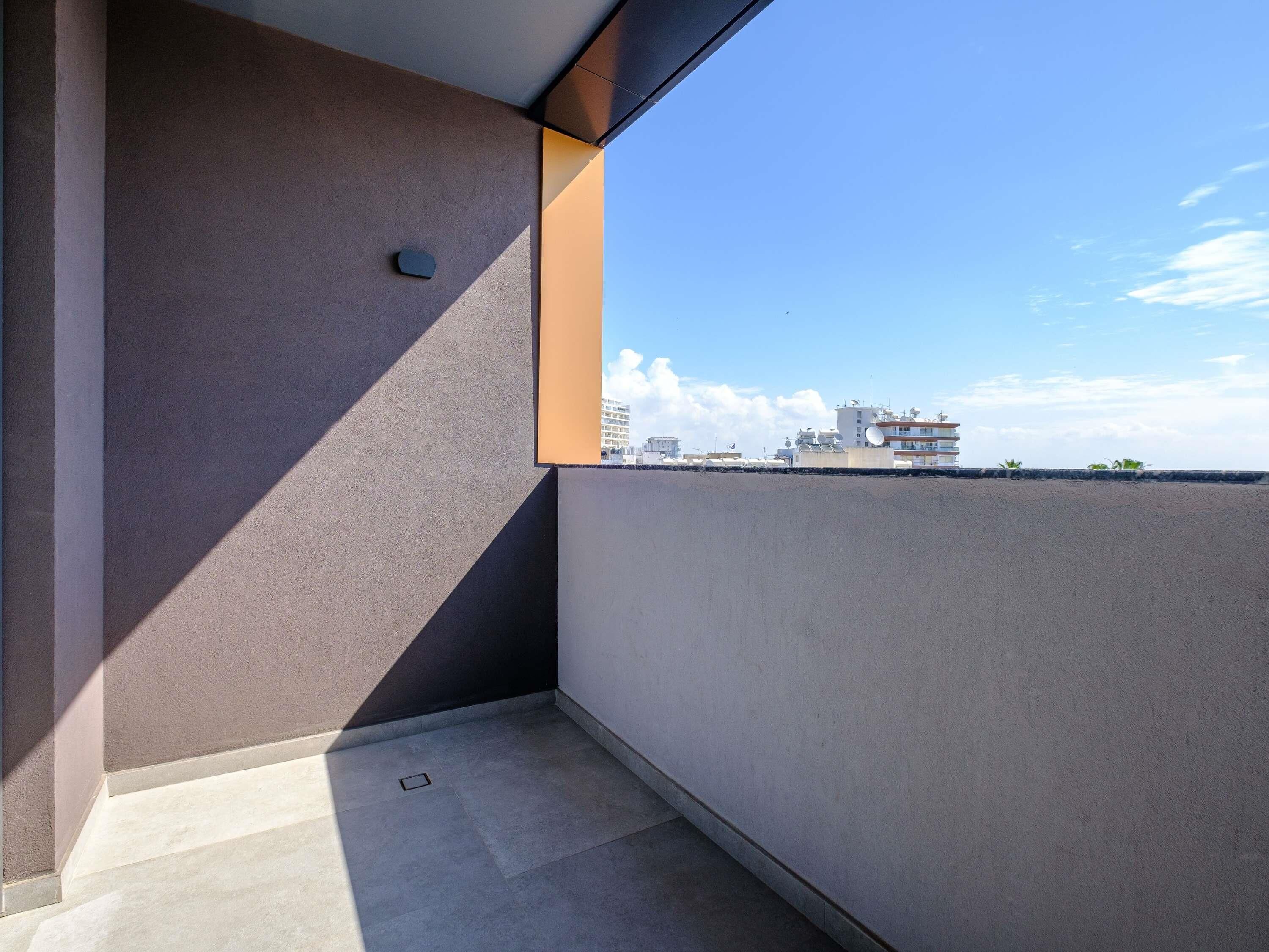 A modern balcony with a view of buildings and a clear sky.