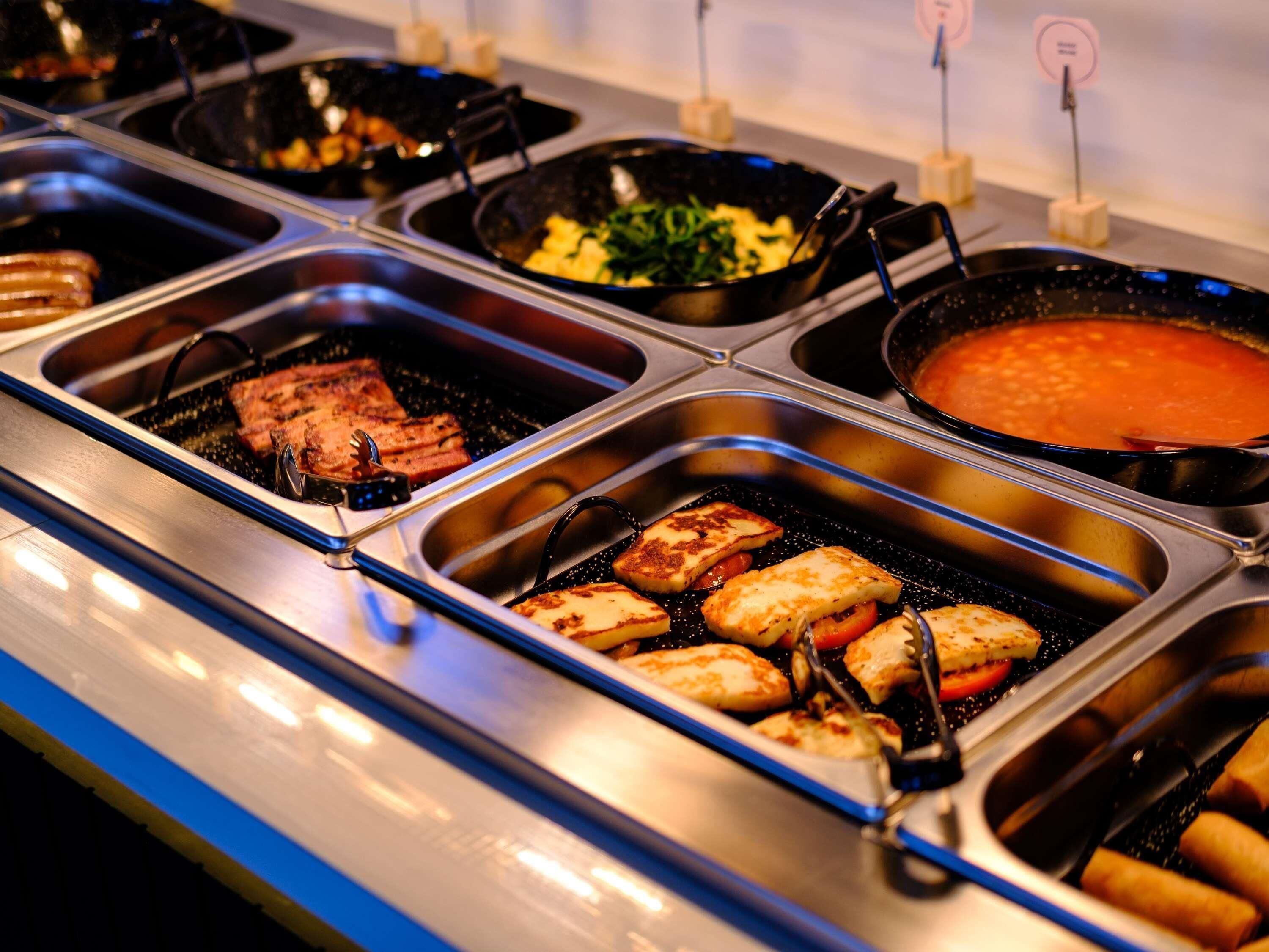 A buffet with various food items including grilled meat, vegetables, and a soup station.