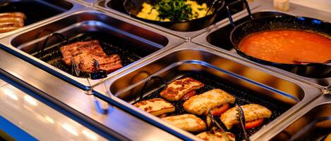 A buffet with various food items including grilled meat, vegetables, and a soup station.