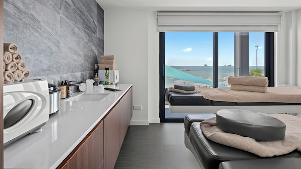 A modern kitchen with a large island, a seating area with a view of the sea, and a large window. - Mercure Larnaca Finikoudes Beach (Larnaca)
