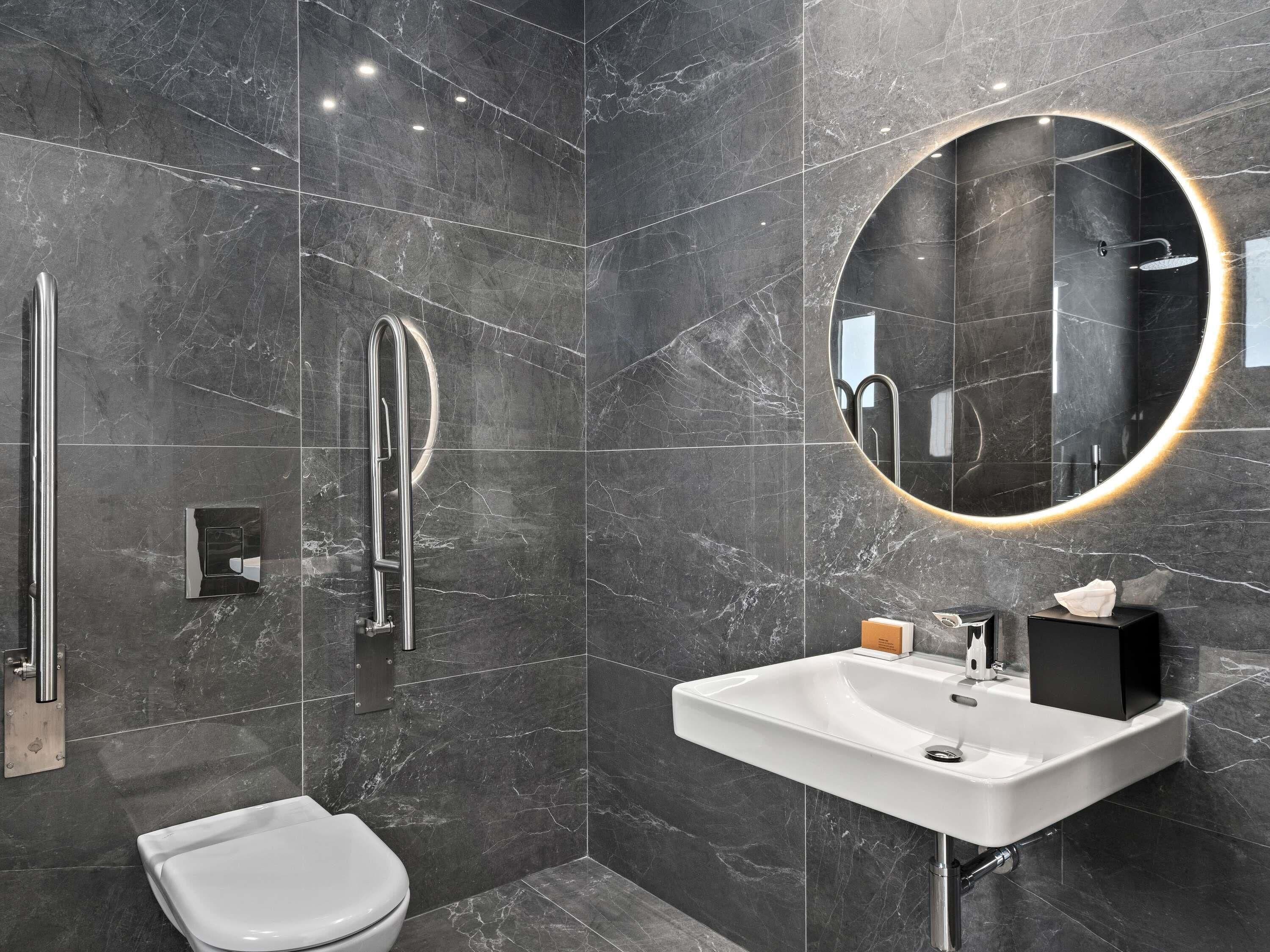A modern bathroom with a toilet, a sink, a mirror, and a shower.