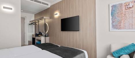 A modern bedroom with a bed, a TV, a chair with a towel, and a painting on the wall.