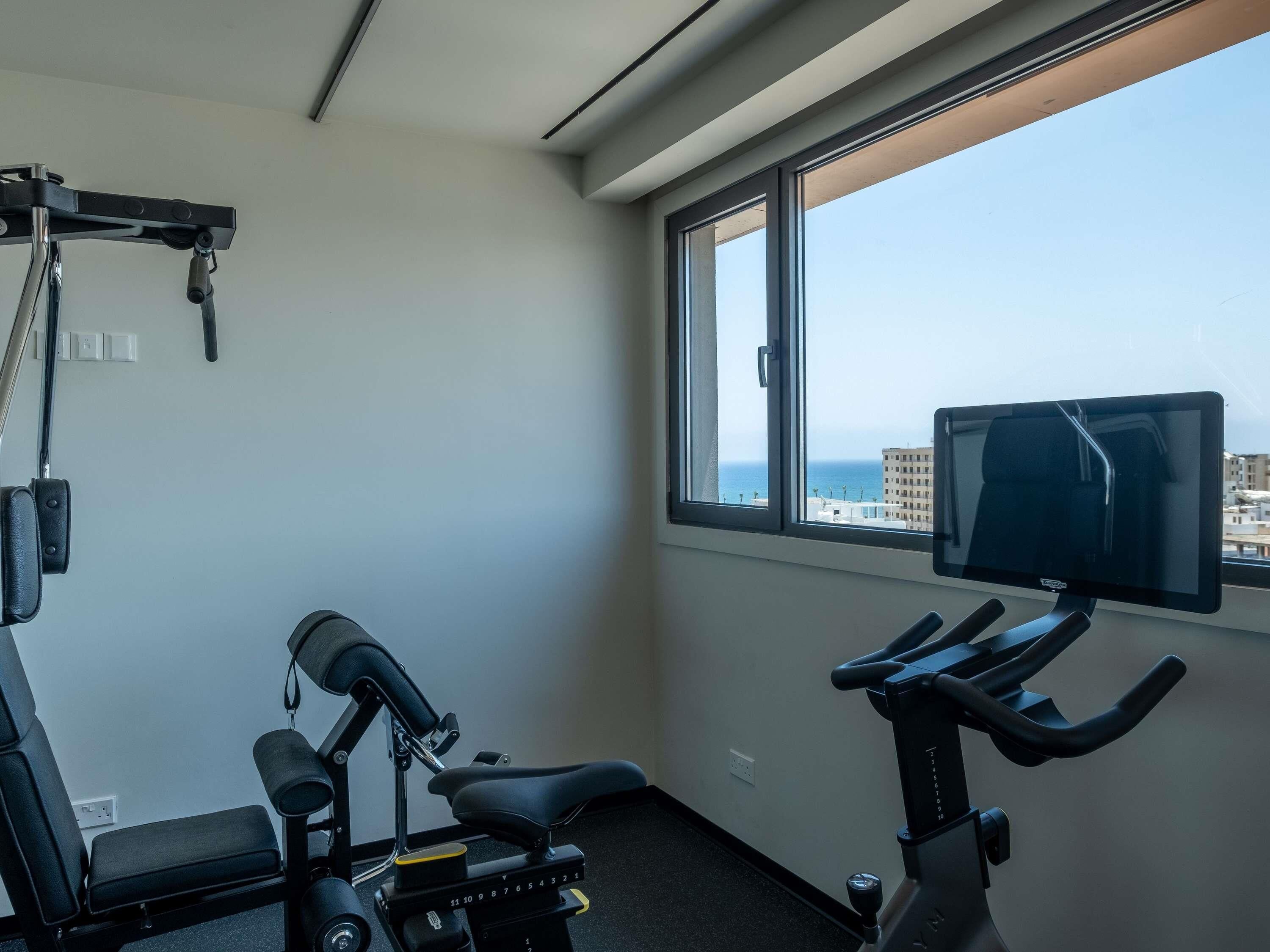 A gym with a stationary bike, a bench, and a weight machine.