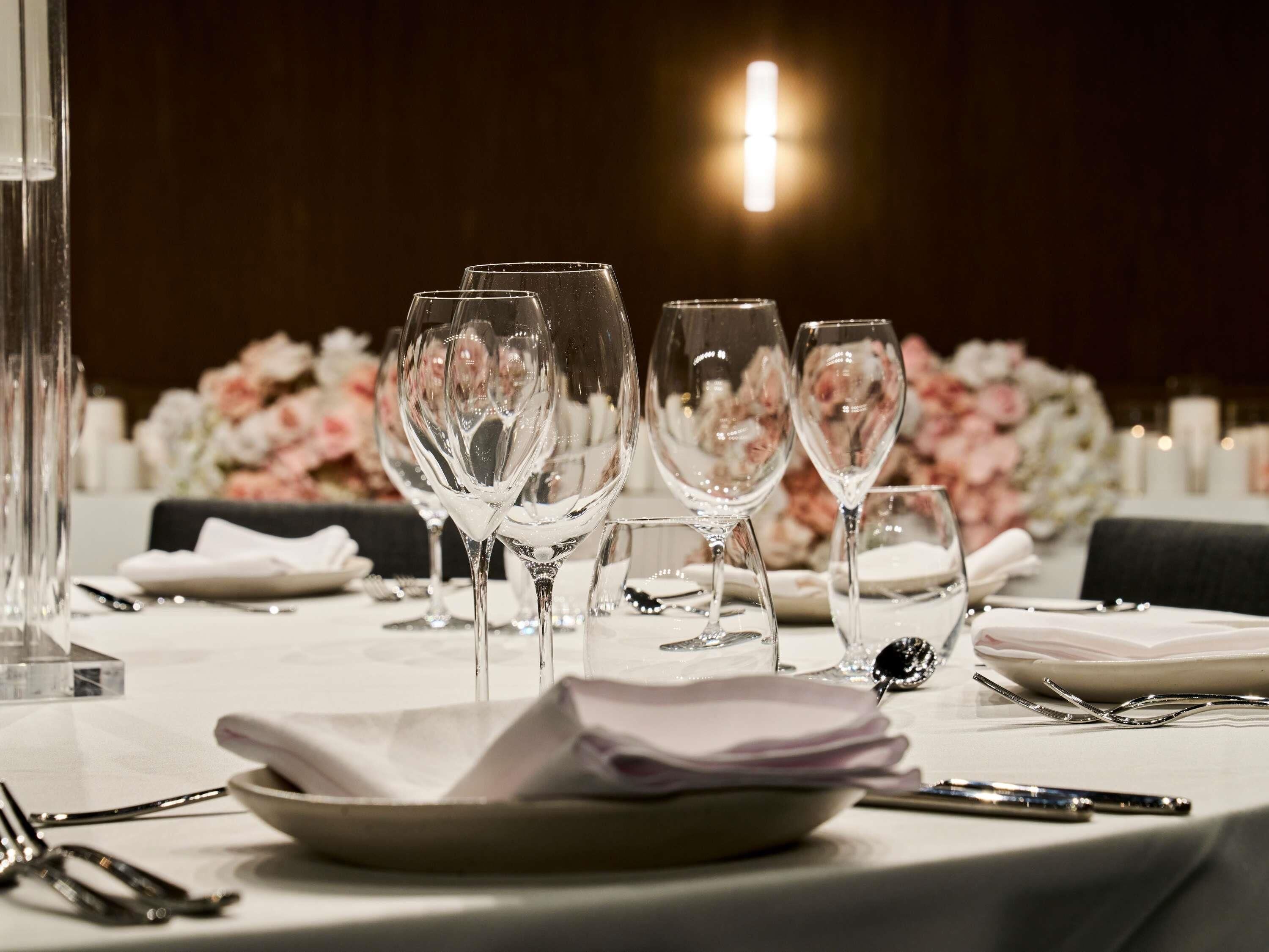 Mesa lista para comer con cristalería, platos y cubiertos.