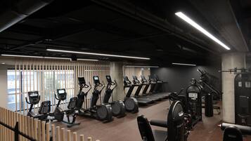 Un gimnasio con cintas de correr, elípticas y equipos de pesas.