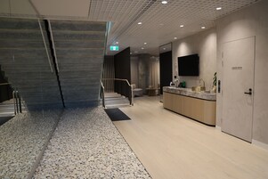 Una hall moderna di un hotel con una reception, una scala e un bagno.