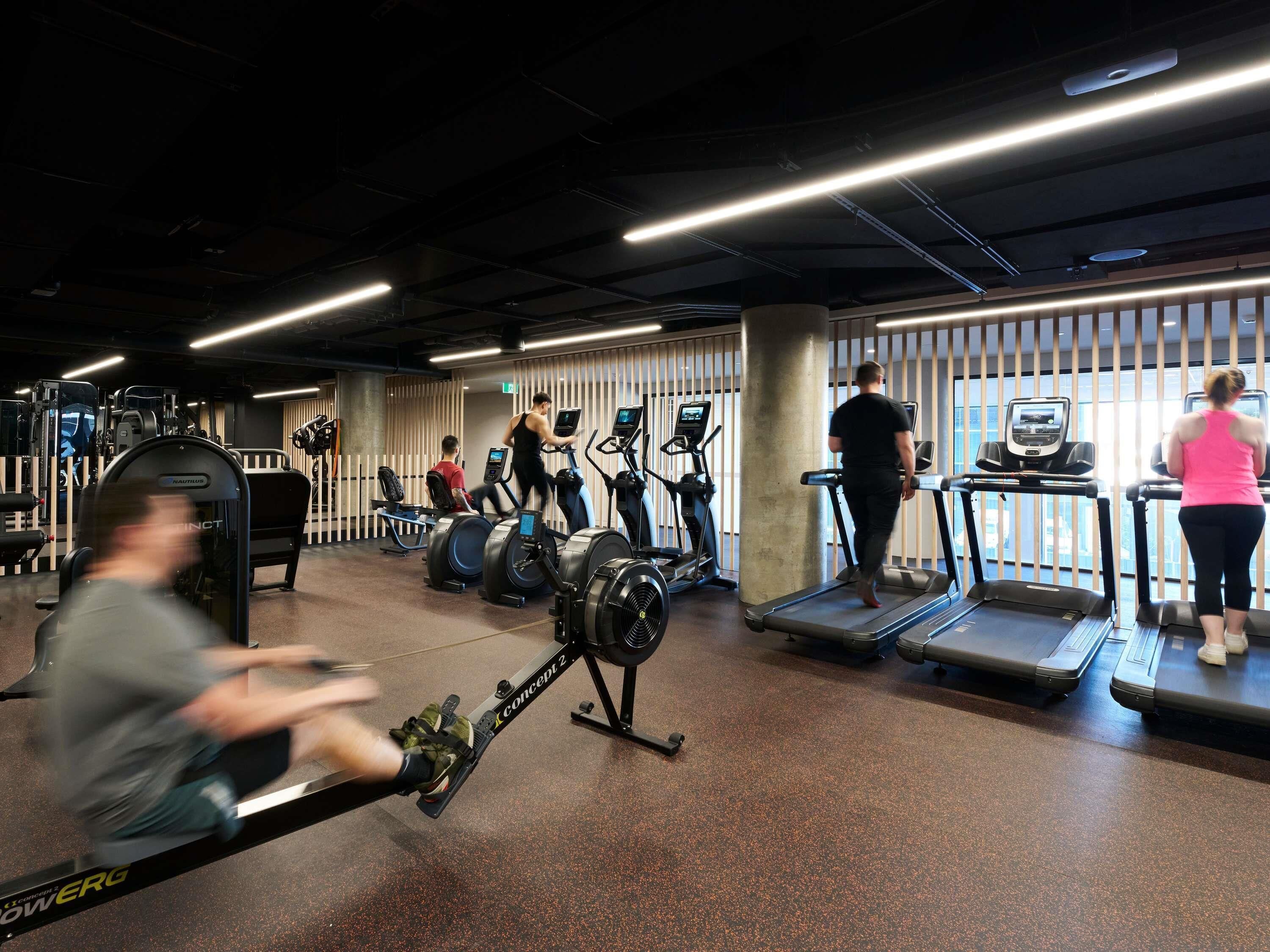 Een sportschool met loopbanden, elliptische trainers en gewichten.