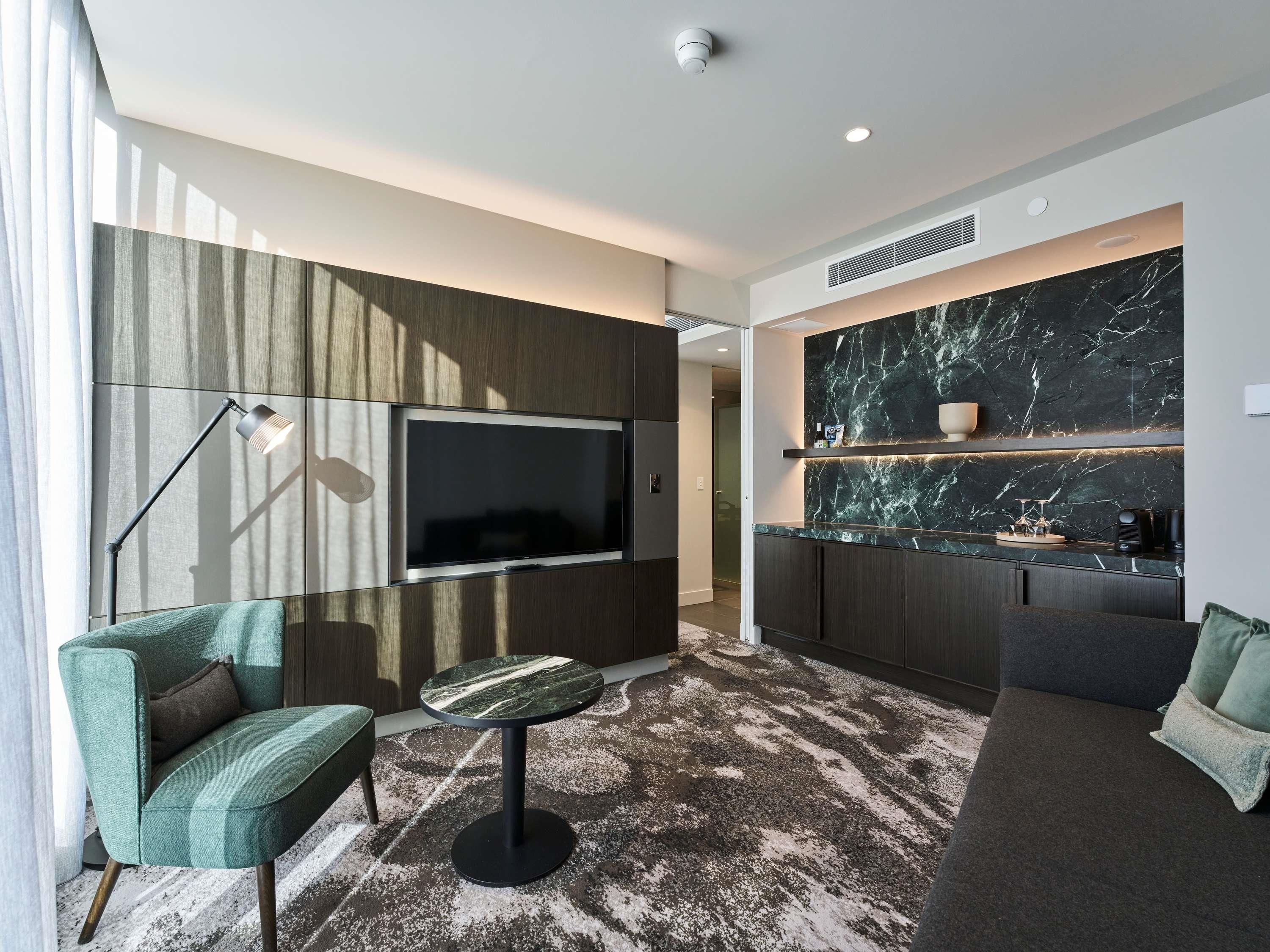 A modern living room with a flat-screen TV, a round coffee table, and a sofa.