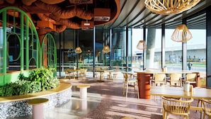 Een modern restaurantinterieur met grote ramen, houten meubels en bijzondere hanglampen.