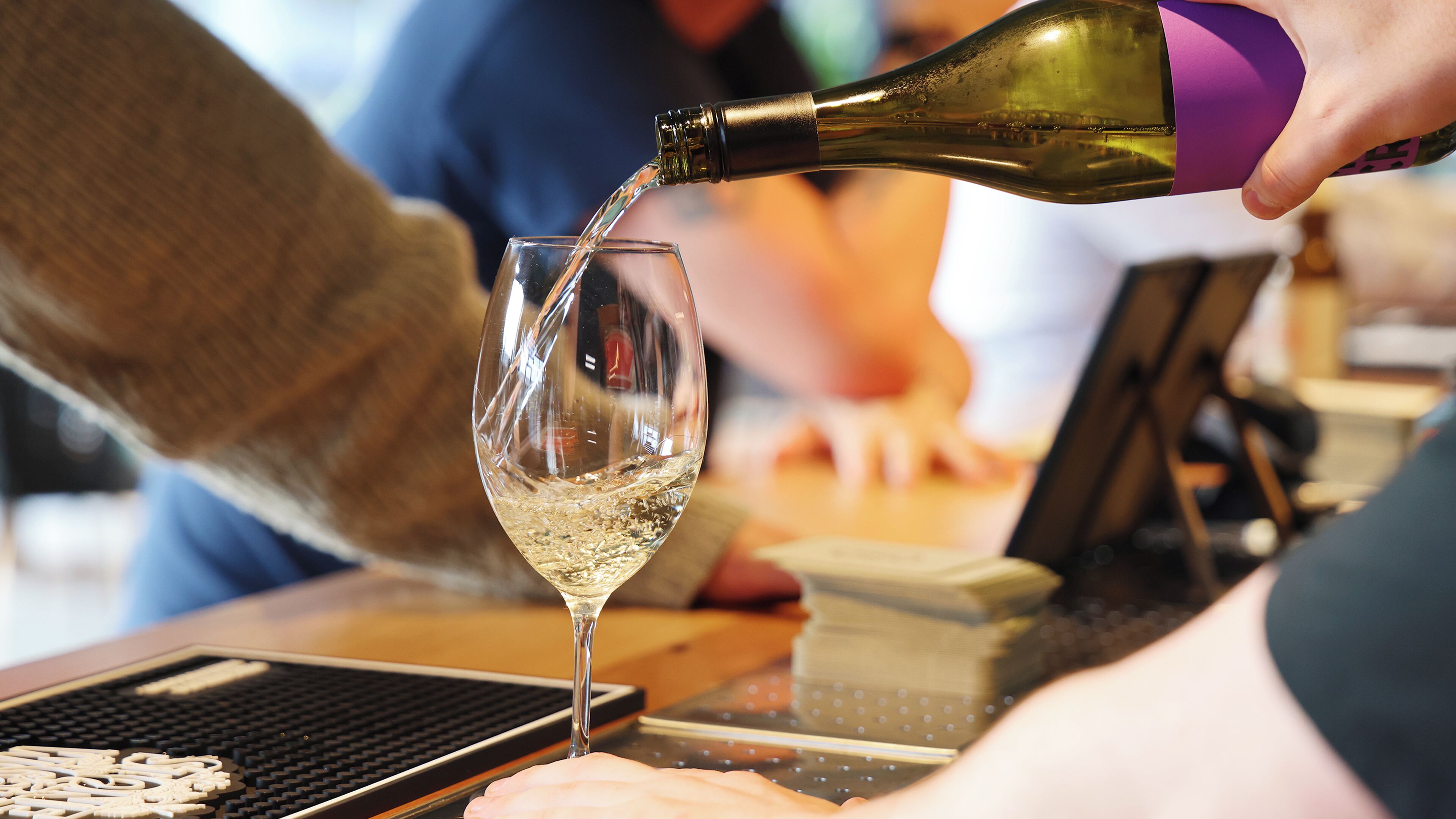 Eine Person gießt eine klare Flüssigkeit aus einer Flasche in ein Glas.