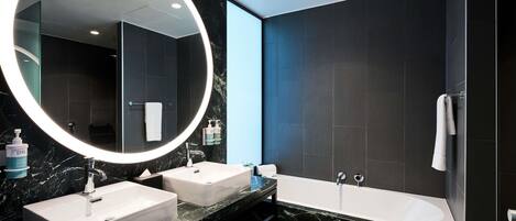 Un baño moderno con dos lavamanos, un espejo grande y una bañera.