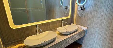 Un baño moderno con dos lavamanos, un espejo grande y un perchero para toallas.
