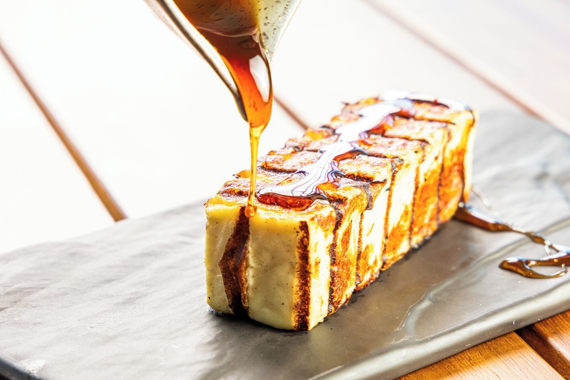 A rectangular serving dish with a rectangular food item, possibly a dessert, on a wooden surface.