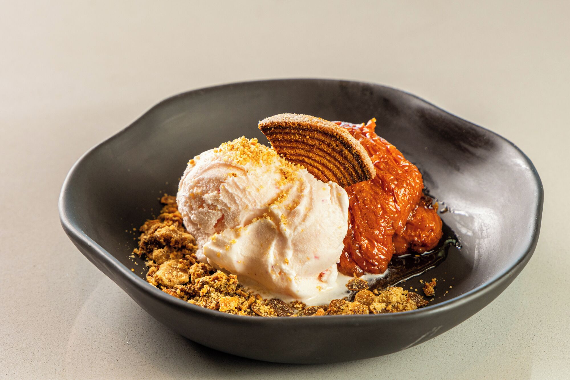 Un dessert con gelato, caramello e un biscotto.