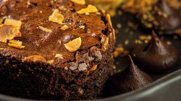 A dessert plate with a chocolate cake topped with almonds, a scoop of vanilla ice cream, and chocolate kisses.