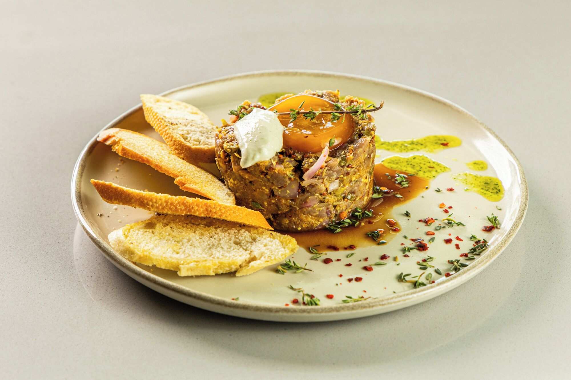 Un plato con un guiso de carne, pan y salsa.