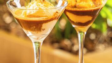 Deux verres à dessert sur une table en bois, avec un arrière-plan flou de couleur verte.