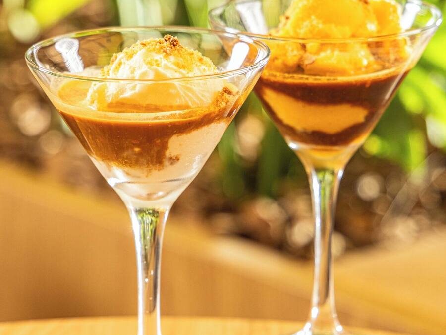 Deux verres à dessert sur une table en bois, avec un arrière-plan flou de couleur verte.