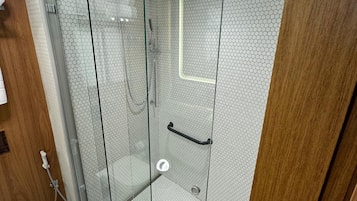 Un baño moderno con ducha de vidrio, inodoro y lavamanos.