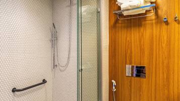 Ein Badezimmer mit einer gläsernen Duschkabine, einem Holzbadezimmermöbel und einer Toilette.