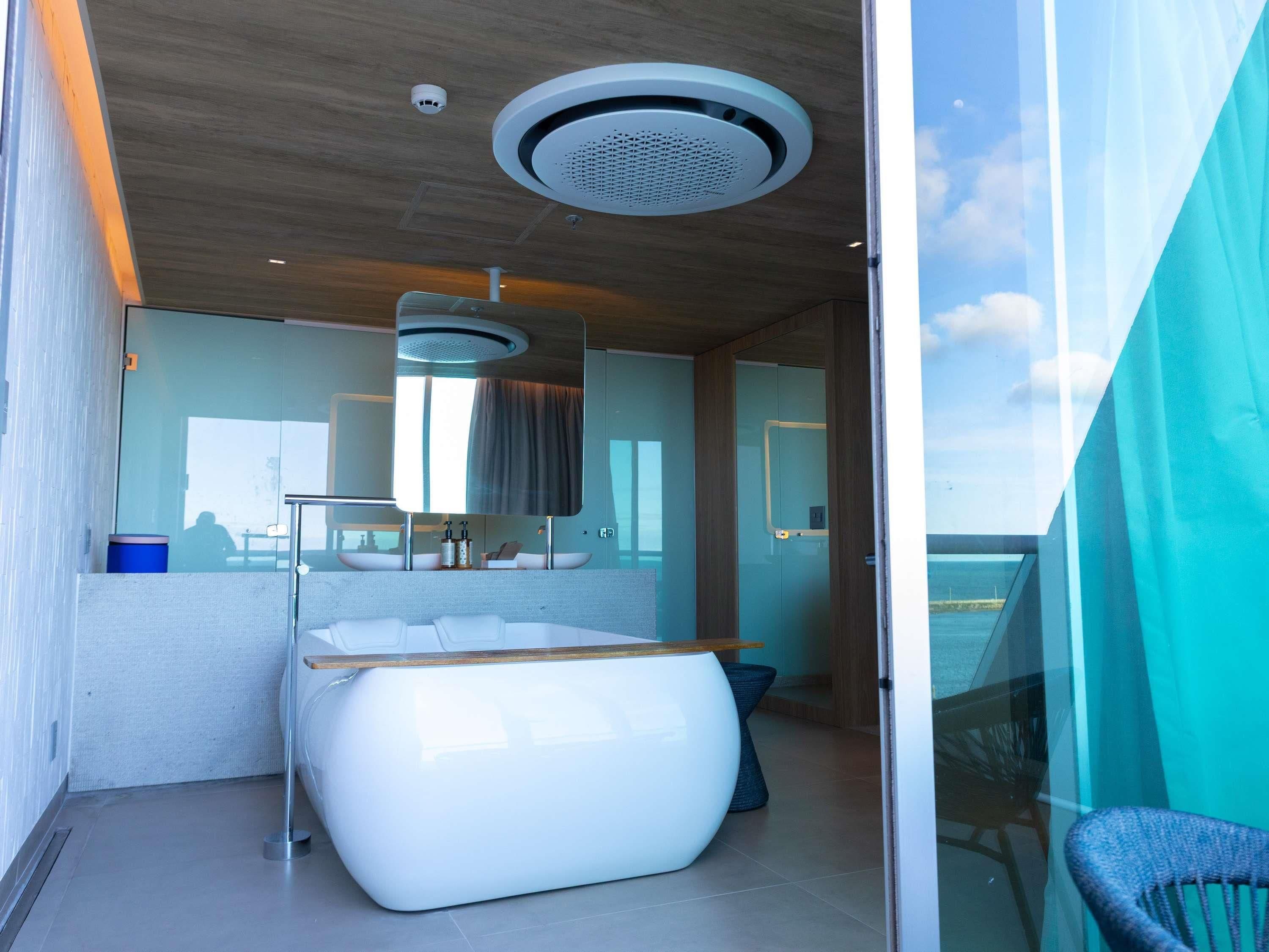 Une salle de bain moderne avec une baignoire, une douche à l’italienne en verre et une vue sur la mer.