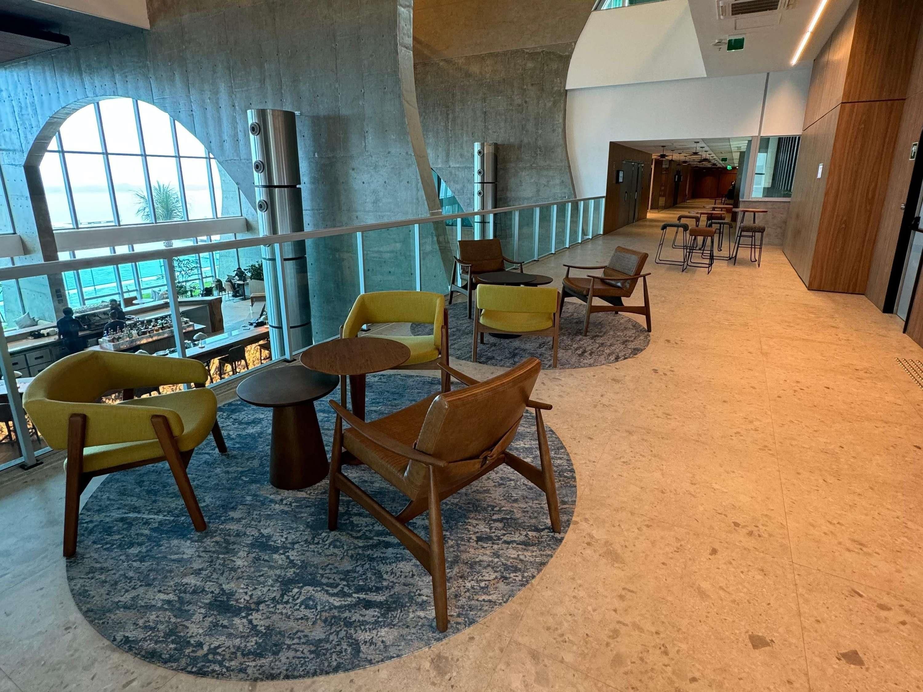 A modern lounge area with seating, a large arched window, and a view of the outdoors.