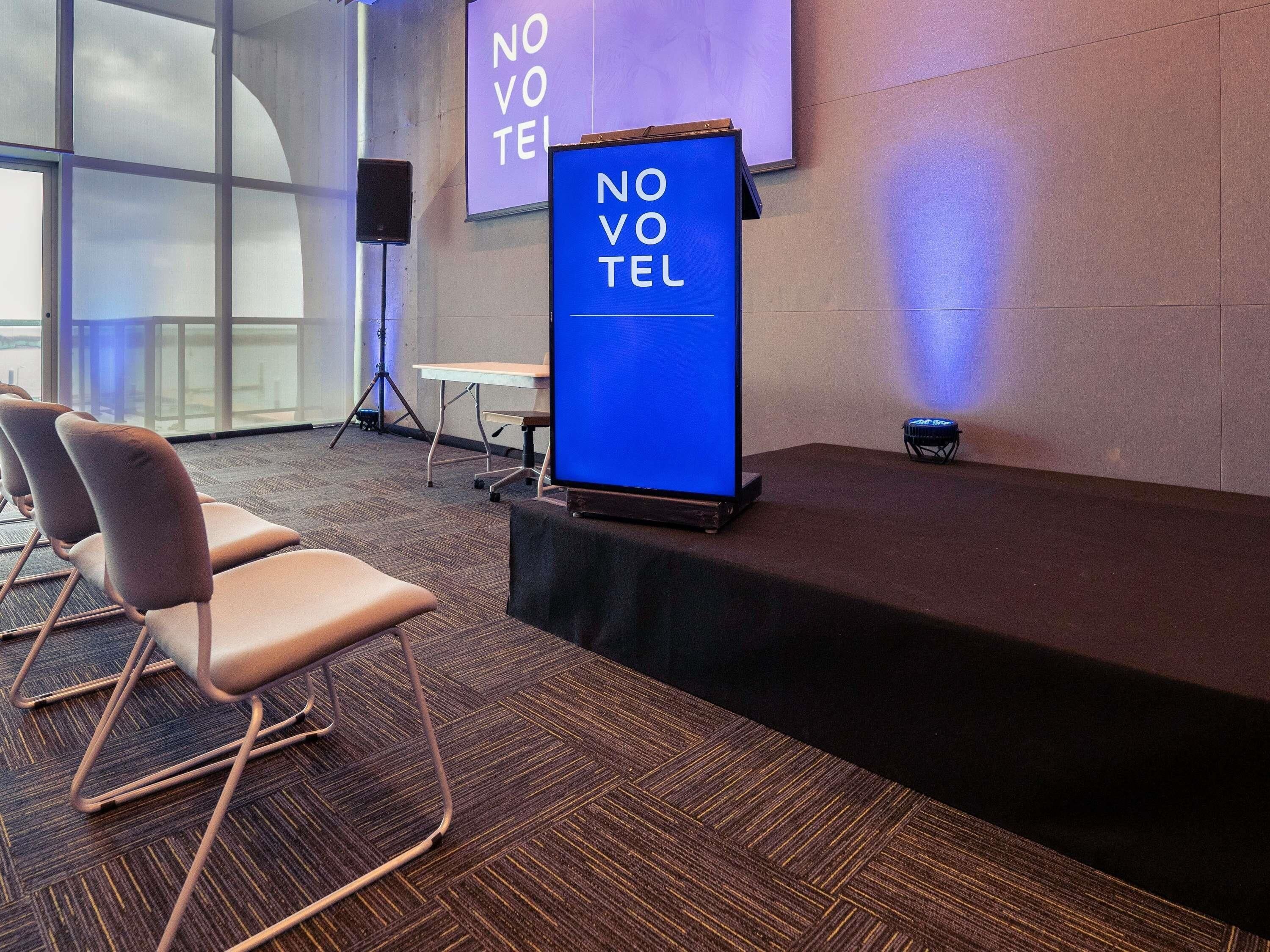 A conference room with a podium, chairs, and a projector screen.