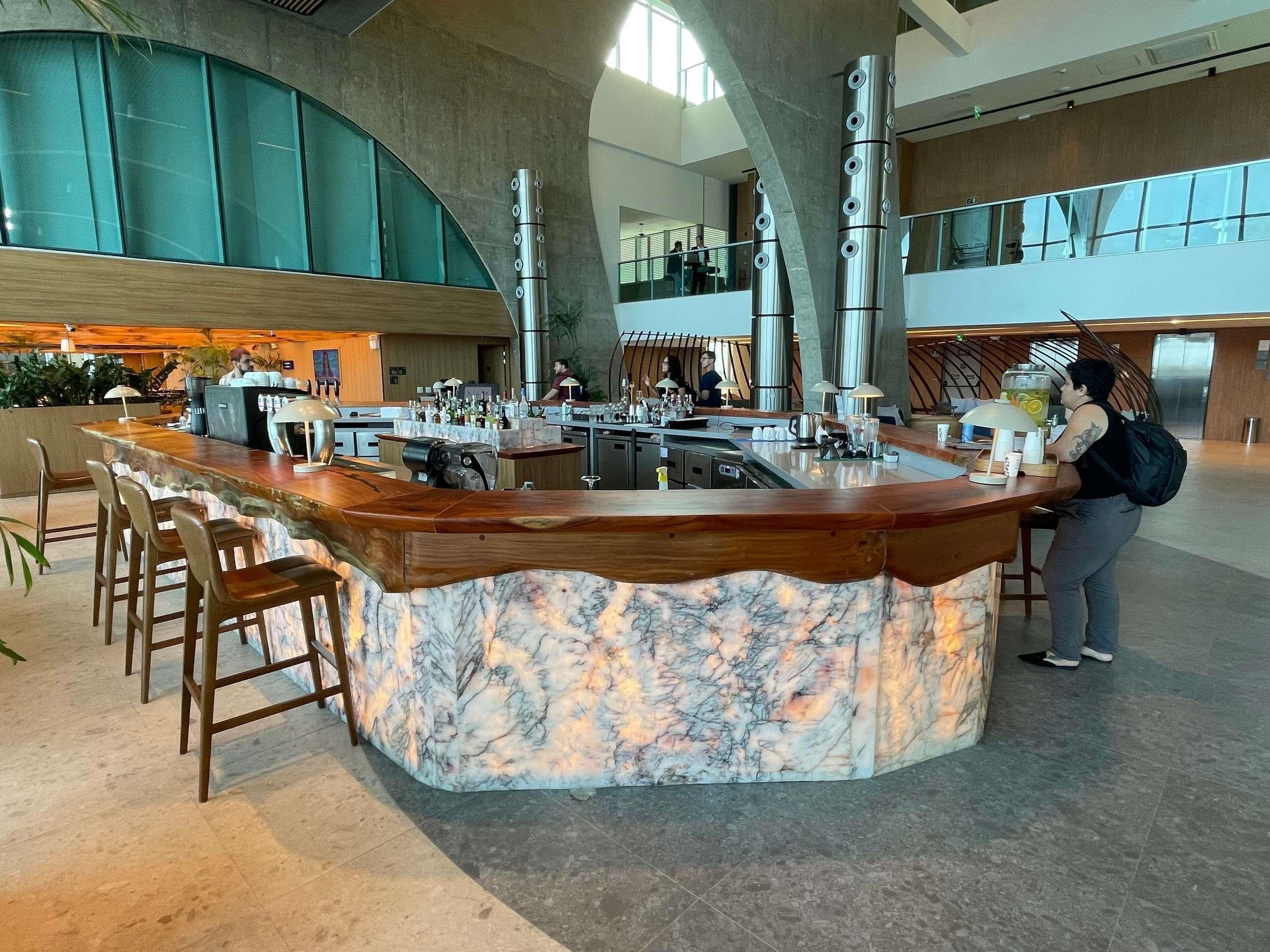 A marble bar with stools, a coffee machine, and a person standing by the bar.