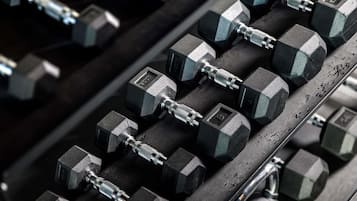 A rack of hexagonal dumbbells with adjustable weights.