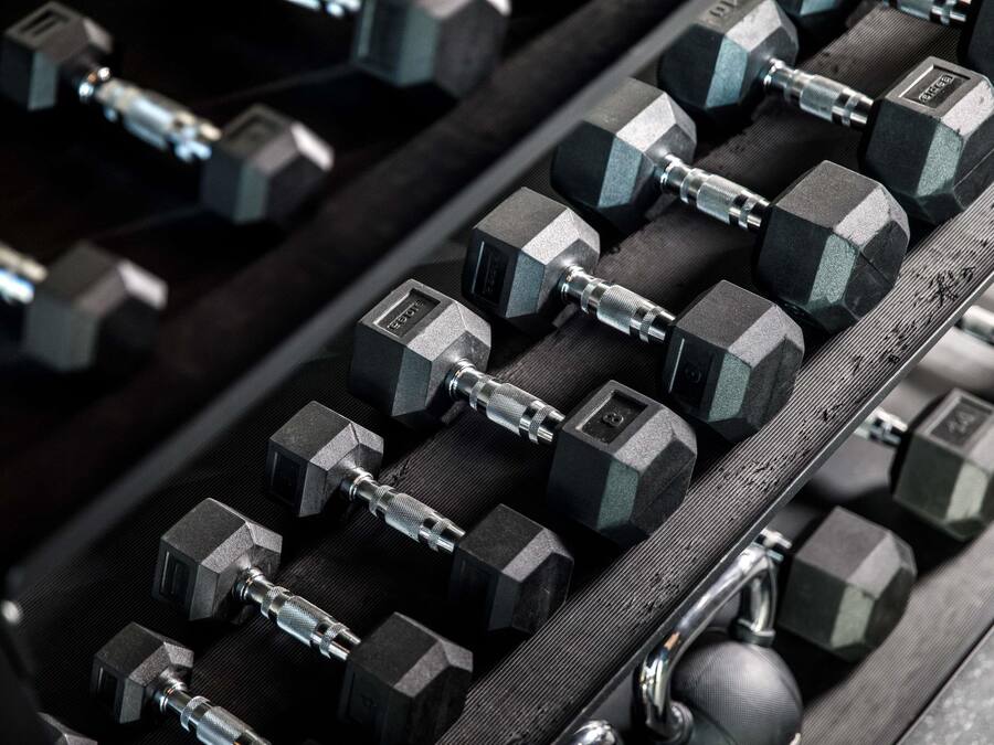 A rack of hexagonal dumbbells with adjustable weights.