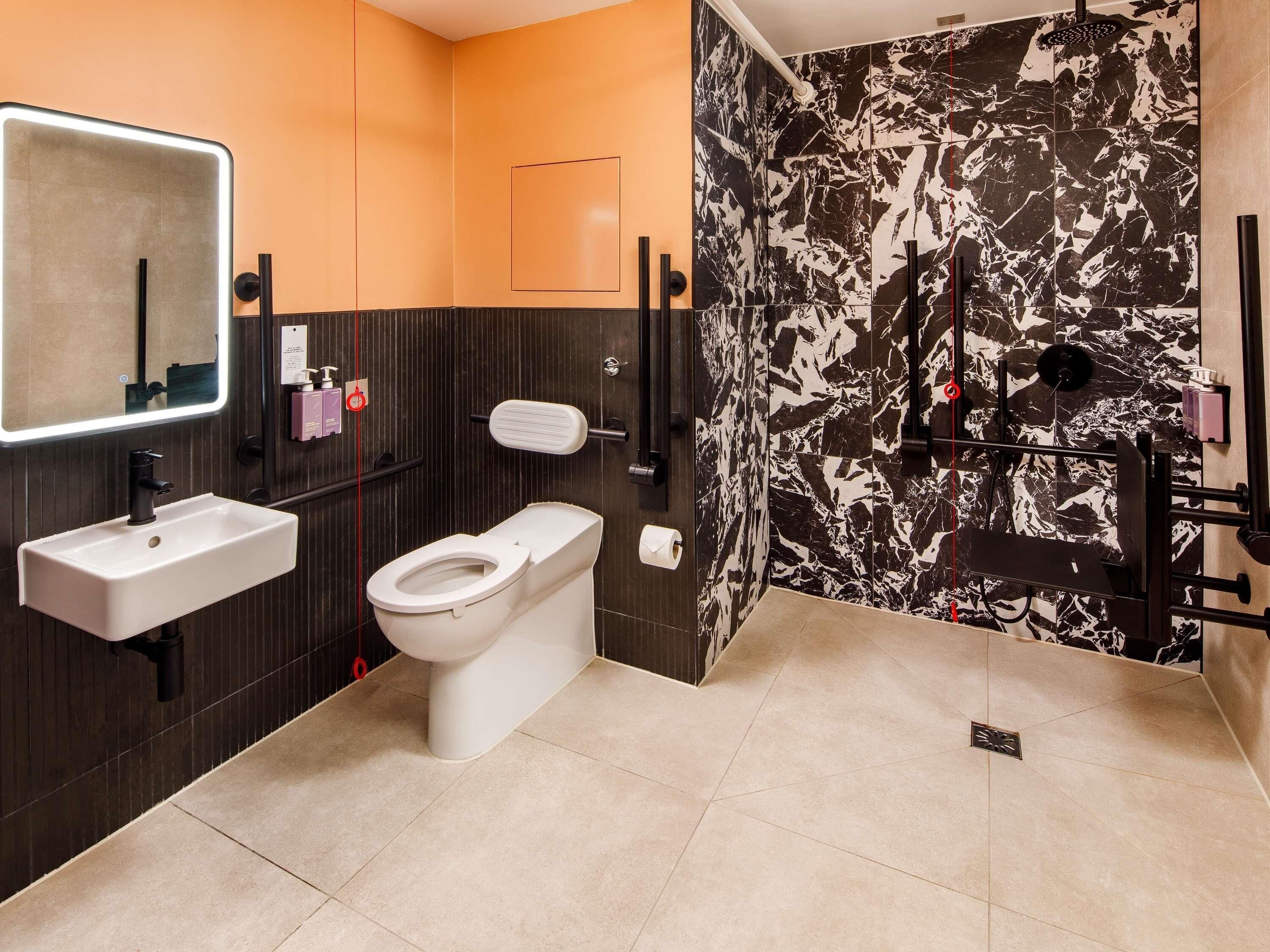 Une salle de bain moderne avec un lavabo, des toilettes et une zone de douche, le tout de couleur blanche.