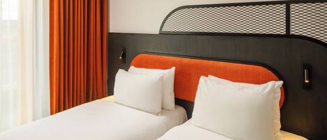 Cama doble con ropa blanca y cabecera naranja, dos almohadas blancas y cabecera de malla negra.