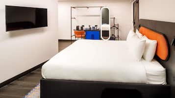 A hotel room with a large bed, a flat-screen TV mounted on the wall, a desk with a chair, and a mirror.