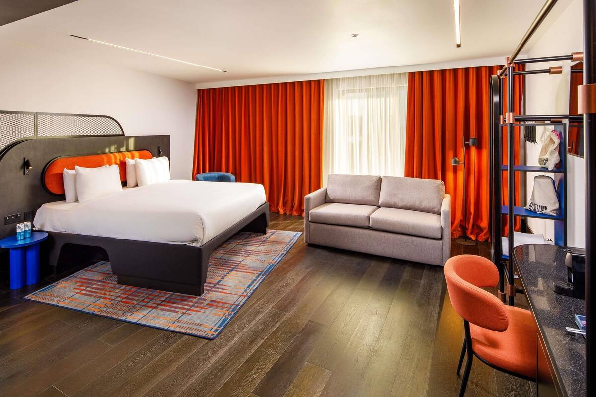 Una habitación de hotel moderna con cama, sofá y zona de escritorio.