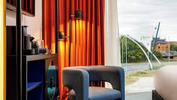 Habitación de hotel con vista al Aeropuerto de Manchester, una cama, un escritorio con tetera y una silla.