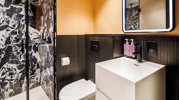 A modern bathroom with a white sink, a toilet, and a shower area.