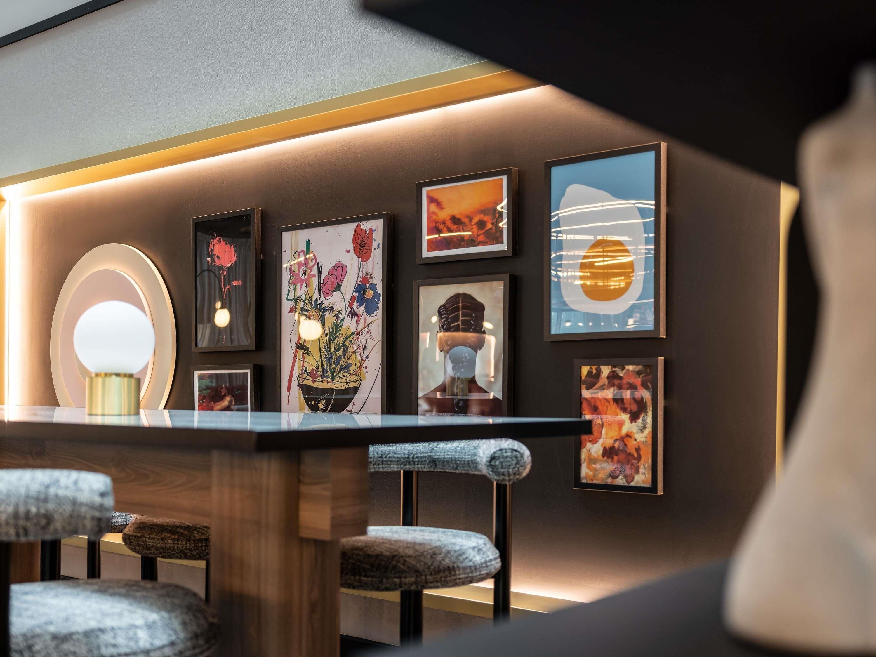 A modern interior with a wooden table, multiple framed artworks, and a unique spherical light fixture.