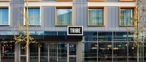 Un edificio moderno con un cartel que dice "TRIBE" sobre la entrada.
