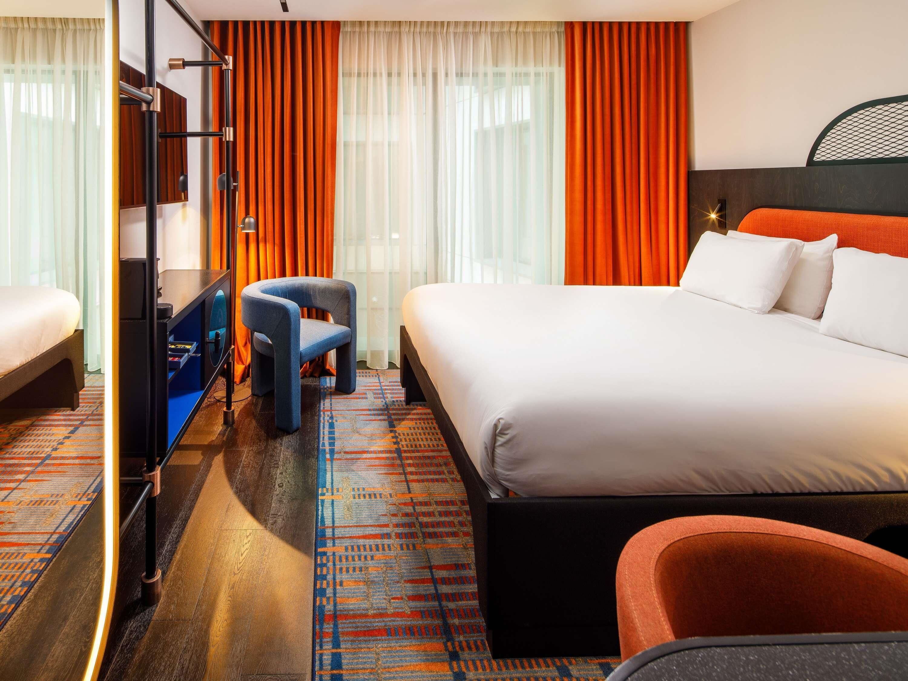 Ein Hotelzimmer mit Bett, Schreibtisch, Stuhl und Fernseher.