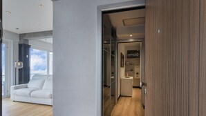 A modern room with a wooden floor, a white sofa, and a glass partition leading to a bathroom. - Stunning Seaview Apartment by Wonderful Italy (Genoa)