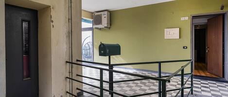 A checkered floor, a metal railing, a door, and a wall-mounted air conditioning unit.