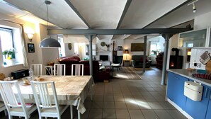 Un amplio salón con una mesa de comedor, sillas, un sofá y una chimenea.