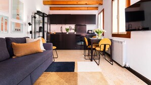 A compact living space with a sofa, dining table, chairs, kitchen area, and artwork on the walls. - Tintoretto Cozy Duplex R&R (Venecia)